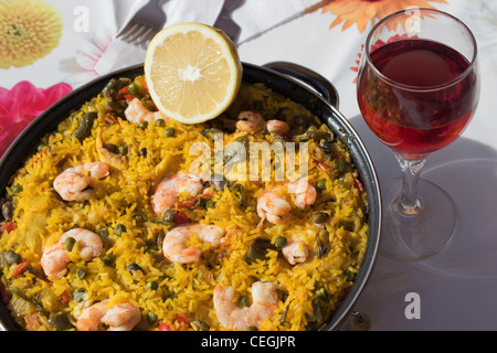 Spanish seafood paella and glass of red wine. Stock Photo