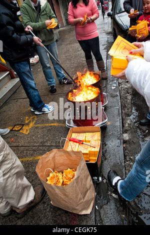 Chinese-American burning symbolic money for luck on the streets of New York City's Chinatown during 2012 Lunar New Year festival Stock Photo