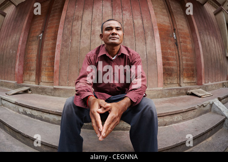 Portrait of mid adult poor asian man with hands joined, looking at camera. Fisheye shot Stock Photo