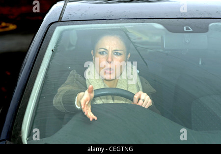 Female in her 20s angry driving a car with road rage shouting at other motorists UK (posed by model) Stock Photo