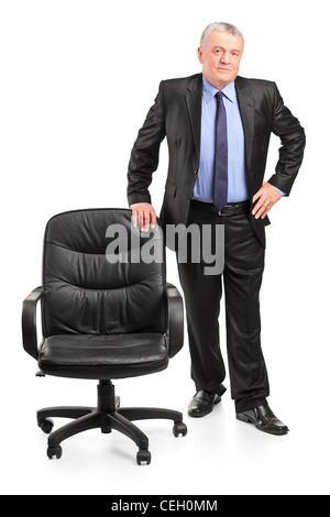 Full length portrait of a mature businessman standing next to a chair isolated on white background Stock Photo