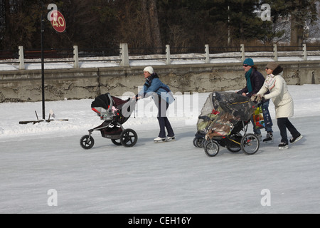 Three moms pushing strollers while skating on the Ottawa Canal Stock Photo