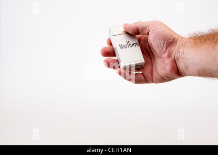 A mans hand holds a small packet of ten cigarettes. The brand is Marlboro lights in a white box or packet Stock Photo