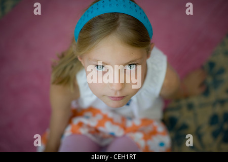 Close up of a ten year old girl wearing a headband looking up. Stock Photo