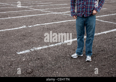 Anonymous man standing in empty parking lot
