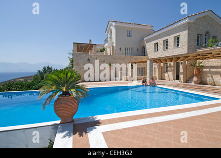 Luxury villa and exclusive private infinity pool overlooking Crete and Aegean sea with palms and typical grecian urns Stock Photo