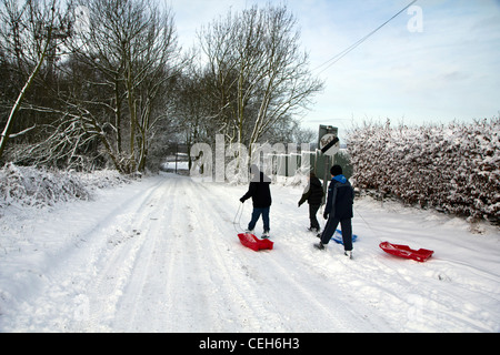 Three young boys/children going sledging after snowfall in Derbyshire Chesterfield England Stock Photo