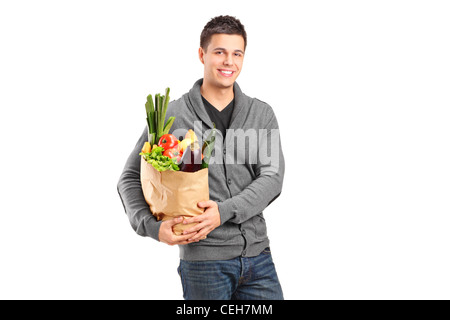 A smiling male holding a paper bag full of groceries isolated on white background Stock Photo