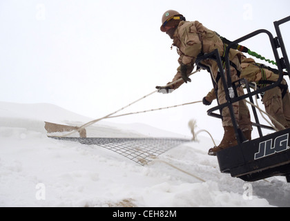 Seabees assigned to Detail Wolverine of Naval Mobile Construction Battalion 7 perform emergency snow removal from berthing facilities at Forward Operating Base Wolverine in southern Afghanistan after a severe snow storm hit the area. NMCB-7 and its detachments are one of two Seabee battalions supporting the International Security Assistance Force as part of Task Force Forager operating in the U.S. Central Command area of responsibility. Stock Photo