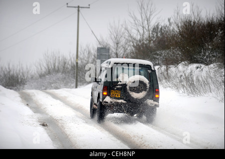 A Land Rover 4x4 negotiates a hill in snowy conditions in Gloucestershire UK Stock Photo