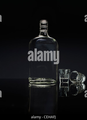 Glass bottle with two empty glasses on Black reflective surface Stock Photo