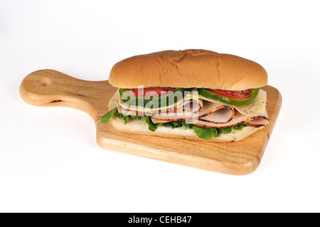 Sliced turkey with cheese, lettuce, tomato and green pepper in submarine sandwich roll on deli board on white background Stock Photo