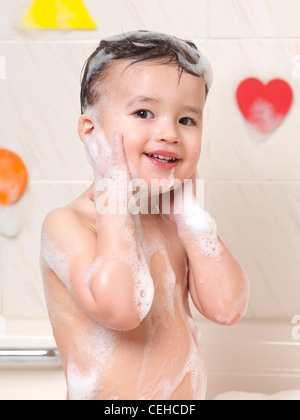Cute smiling two year old baby boy enjoying a foam bath