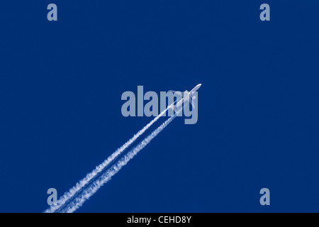 White airliner vapor contrails against blue sky Stock Photo