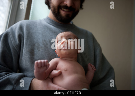 Two and a half month old baby girl looking up, being held by father at home. Stock Photo