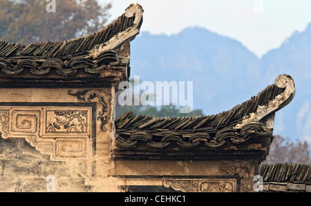 A Chinese Hui Style house with black roof tiles, white wall, and decorated with artworks. Mountains in the background Stock Photo