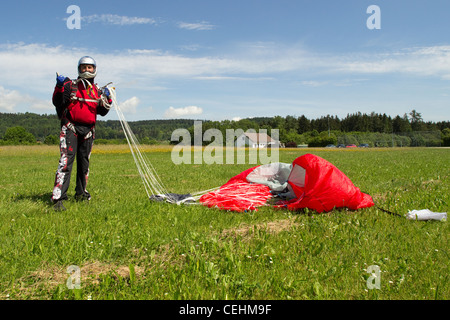 Skydiver over fifty is happy after a successful parachute jump. He's getting his canopy together and smiling in his helmet. Stock Photo