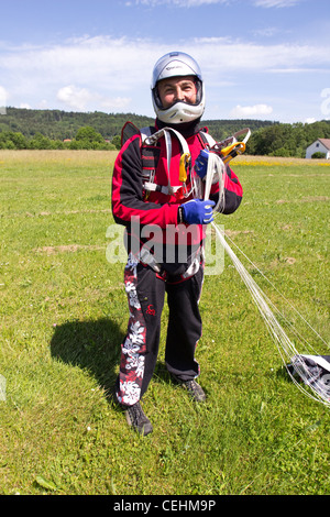 Skydiver over fifty is happy after a successful parachute jump. He's getting his canopy together and smiling in his helmet. Stock Photo