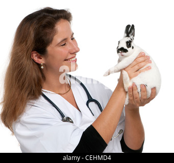 Vet looking at Dalmation rabbit in front of white background Stock Photo