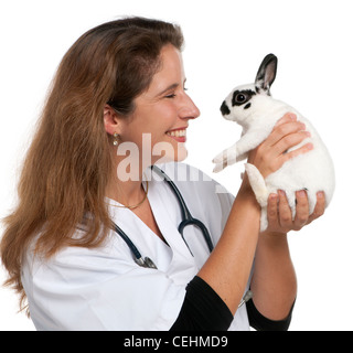 Vet looking at Dalmation rabbit in front of white background Stock Photo
