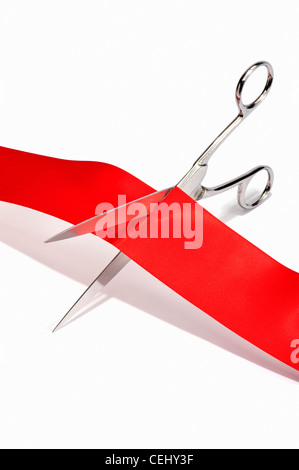 Scissors cutting through a red ribbon Stock Photo