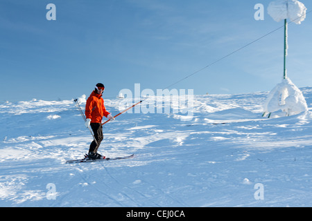 Man skiing in the orange jacket on the lift Stock Photo