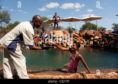 Waiter serving tourist cocktails by the pool,Madikwe Game Lodge,North West Province Stock Photo