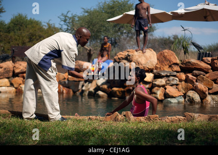 Waiter serving tourist cocktails by the pool,Madikwe Game Lodge,North West Province Stock Photo