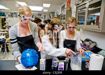 A high school teacher in San Clemente CA, assists her students with a solution chemistry experiment in freezing point depression Stock Photo