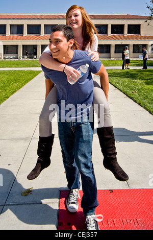 A Hispanic student carries his Caucasian girlfriend piggyback across the campus of Saddleback College in Mission Viejo, CA. Stock Photo