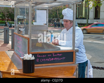 30-40 year old man in cook's uniform working at a creme brulee food cart on Market St. in San Francisco, California. Stock Photo