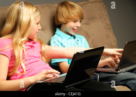 A picture of two siblings using laptop computers on a couch. Stock Photo