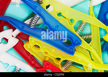 multi coloured plastic pegs on a light blue background Stock Photo