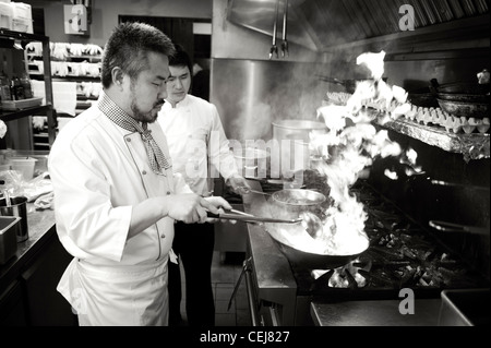 A chef stir frying with a wok, at a Korean restaurant. Stock Photo