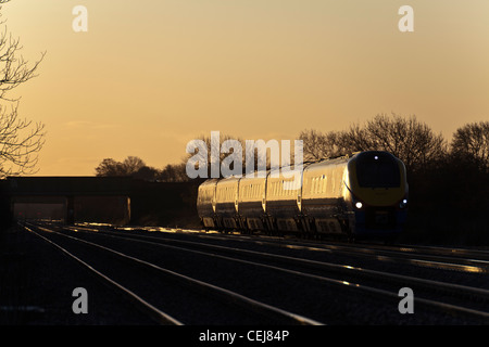 East Midlands Trains class 222 Meridian catches early morning glint sunlight at Cossington foot crossing. Stock Photo