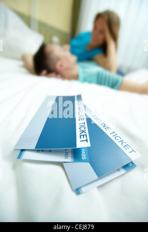 Image of airline tickets on bed with happy young couple at background Stock Photo