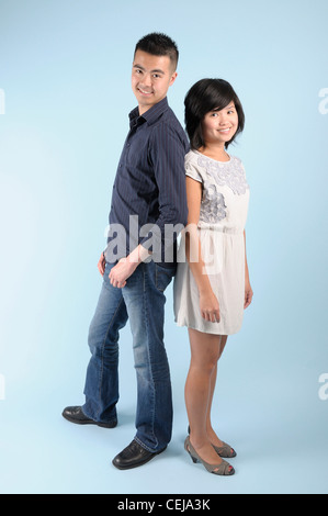 Young Asian couple standing back to back and smiling Stock Photo