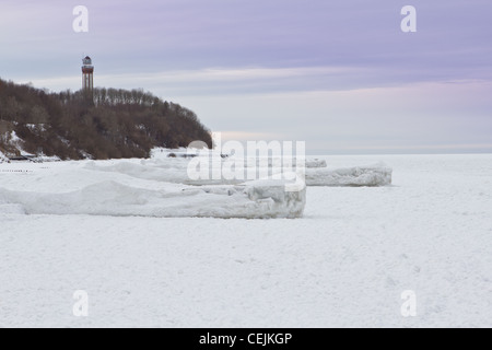 Frozen piers and frozen Baltic Sea, in Niechorze, Poland. In the background you can see the lighthouse. Stock Photo