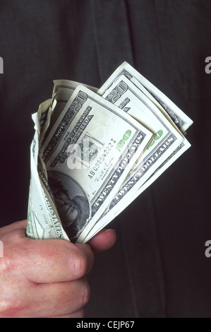 Concept type image close up of Cash in Hand or Fistful of Dollars featuring greenbacks held in a mans clenched fist holding dollar bills to chest Stock Photo