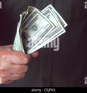 Concept type image close up of Cash in Hand or Fistful of Dollars featuring greenbacks held in a mans clenched fist holding dollar bills to chest Stock Photo