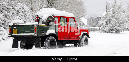 Snow landscape scene Land Rover Defender 130 4x4 pickup driving on narrow country lane road in winter snowfall cold weather Brentwood Essex England UK Stock Photo