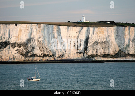Yacht passing along the White cliffs of Dover in the English Channel east of Dover below South Foreland lighthouse. Dawn light Stock Photo