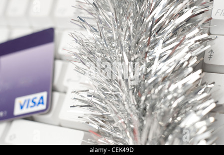 A still life image of a Visa card and silver tinsel lying on top of white computer keyboard Stock Photo