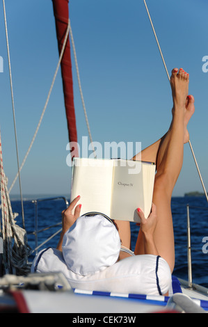 Woman sunbathing and reading on sail boat Stock Photo