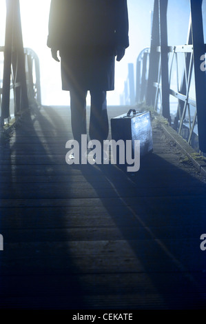 man with case standing on a bridge in fog Stock Photo