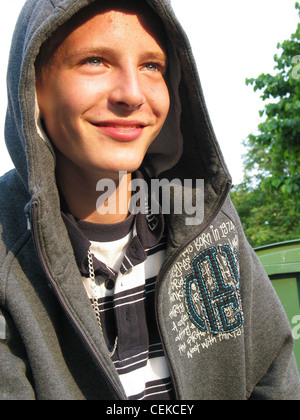 Teenage male wearing grey hooded top looking up past camera smiling showing teeth Stock Photo