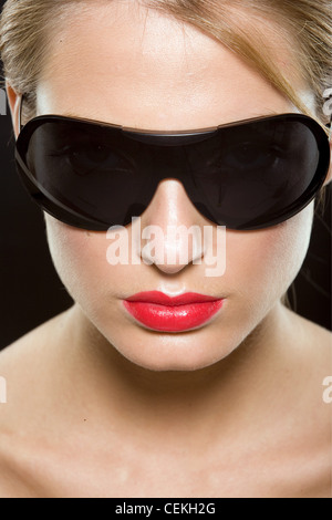 Female with blonde hair wearing worn tied up wearing bright red lipstick and large black sunglasses Stock Photo