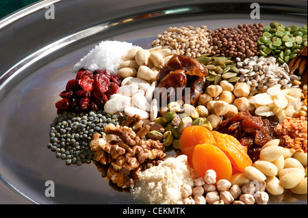Close up of a colourful range of pulses, nuts, seeds and dried fruits on a silver oval tray. Stock Photo