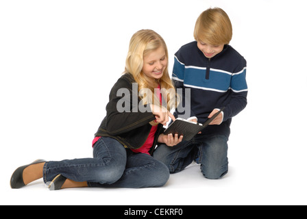 Ten year old girl and eleven year old boy using tablet computers or eBook readers and smiling. Stock Photo