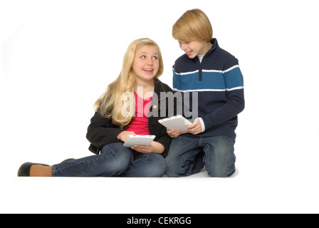 Ten year old girl and eleven year old boy using tablet computers or eBook readers and smiling. Stock Photo